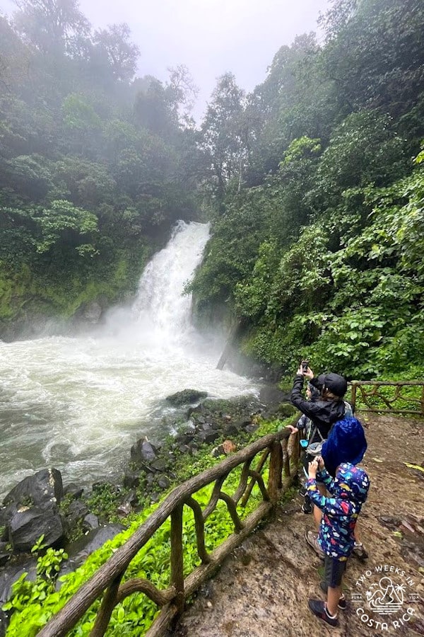 people at a waterfall viewpoint wearing rain jackets