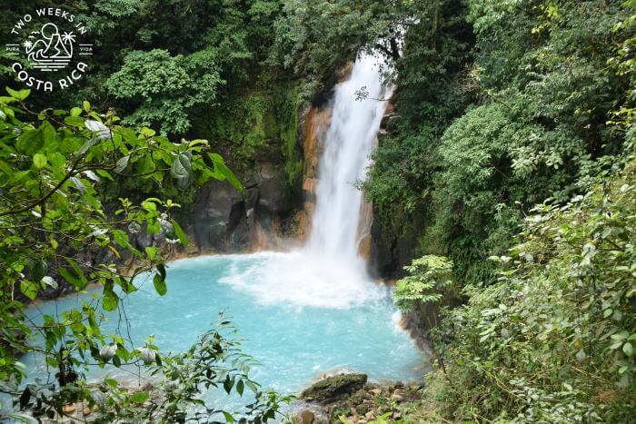blue waterfall from above with green jungle surrounding