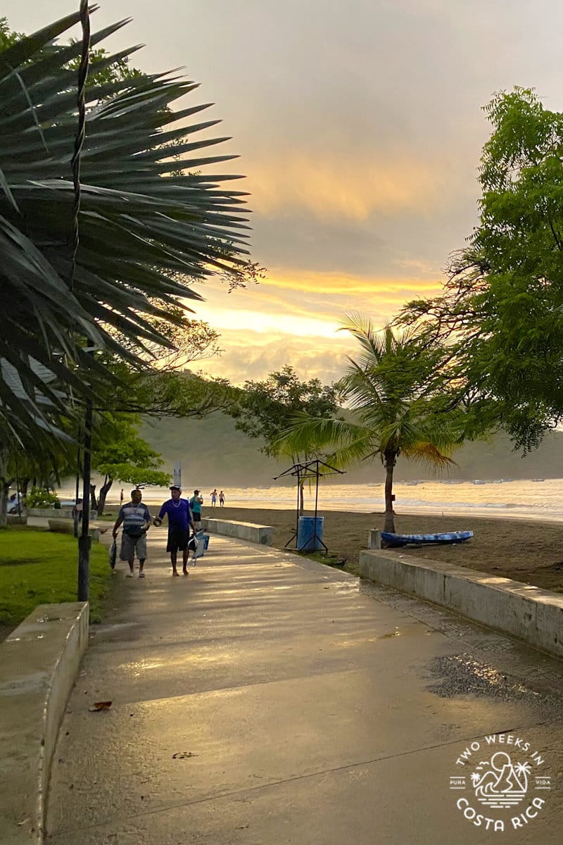 people walking on a concrete path next to the beach