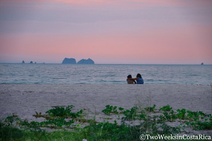 A couple sitting on the beach at sunset in Playa Brasilito, Costa Rica