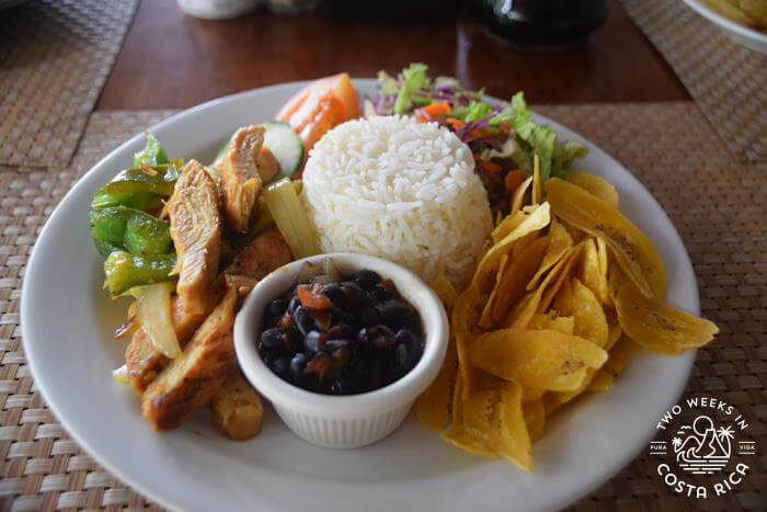 A large plate of food with rice, beans, chips, salad and sauteed chicken with vegetables. 