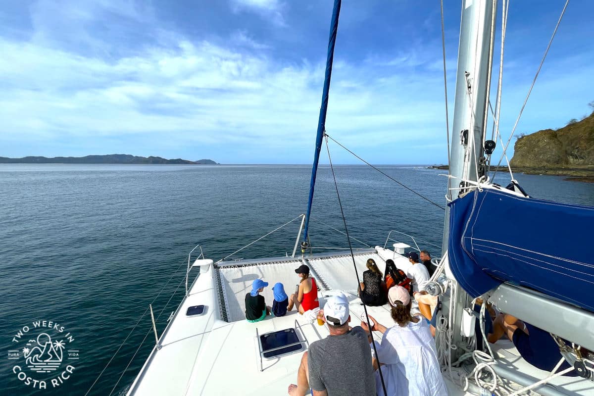 a mom and kids sitting on the front of a catamaran in guanacaste costa rica