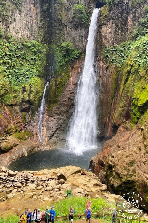tall waterfall flowing into a brown rocky pool