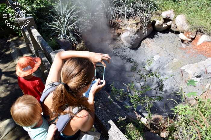 woman with two kids taking a picture of gray bubbling mud