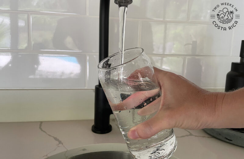 a person filling up a glass of water at the sink