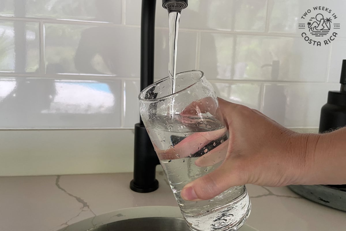 a person filling up a glass of water at the sink