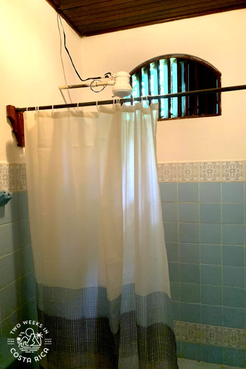 blue bathroom with white electric shower head with wires