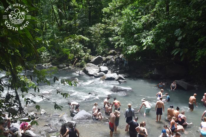 Small crowd gathered in the shallow river along rocks