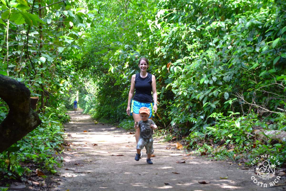 a mom and toddler walking on a trail through the jungle in costa rica