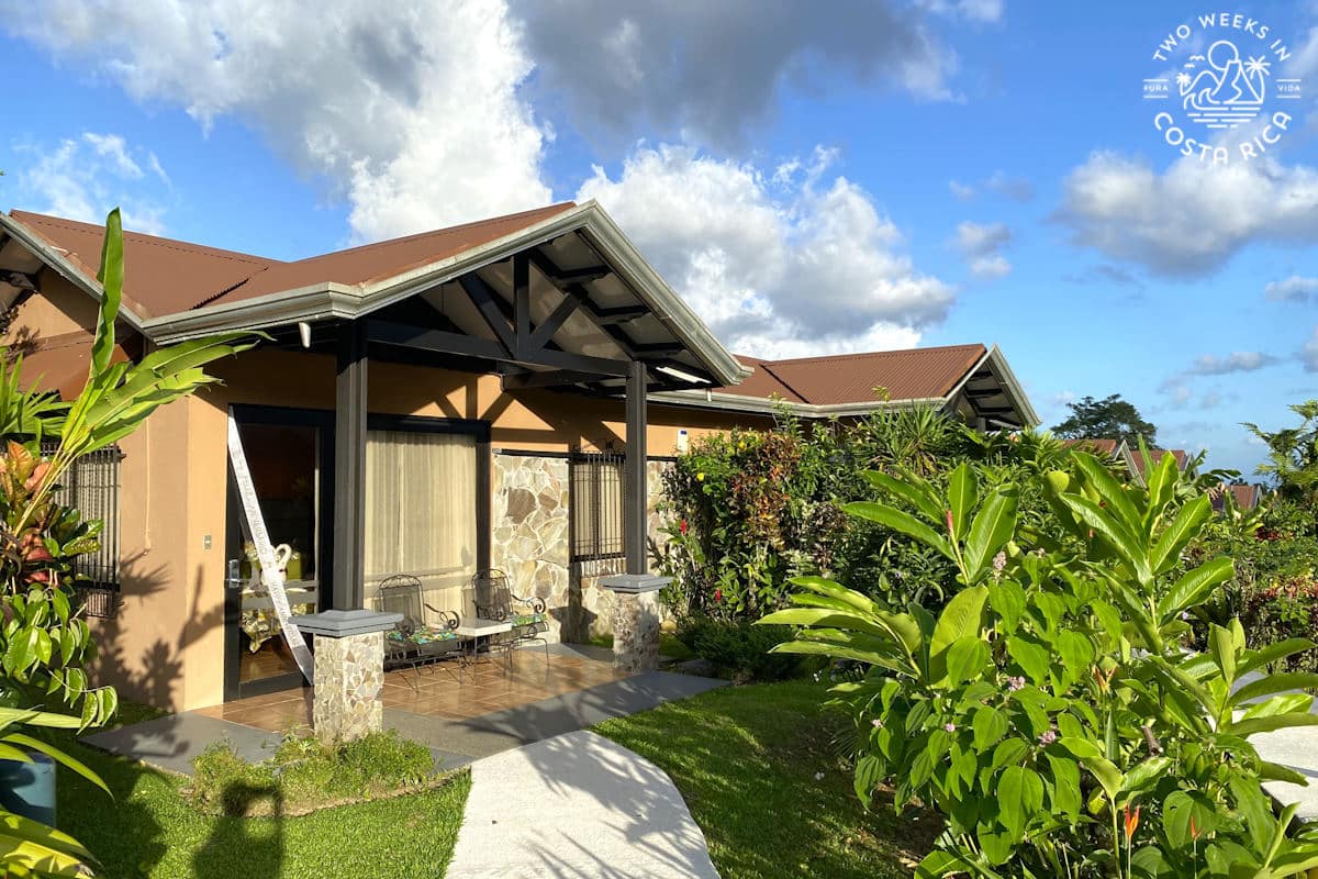 small building with large windows and peaked roof with gardens in the front