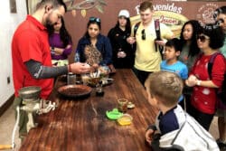 people watching a guide make chocolate on a tour in monteverde