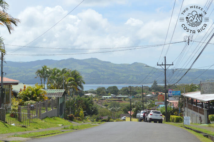 Main road in Nuevo Arenal with houses and view of lake and mountains in distance