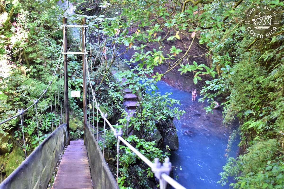 A rustic stairway leading down to a waterfall and blue river
