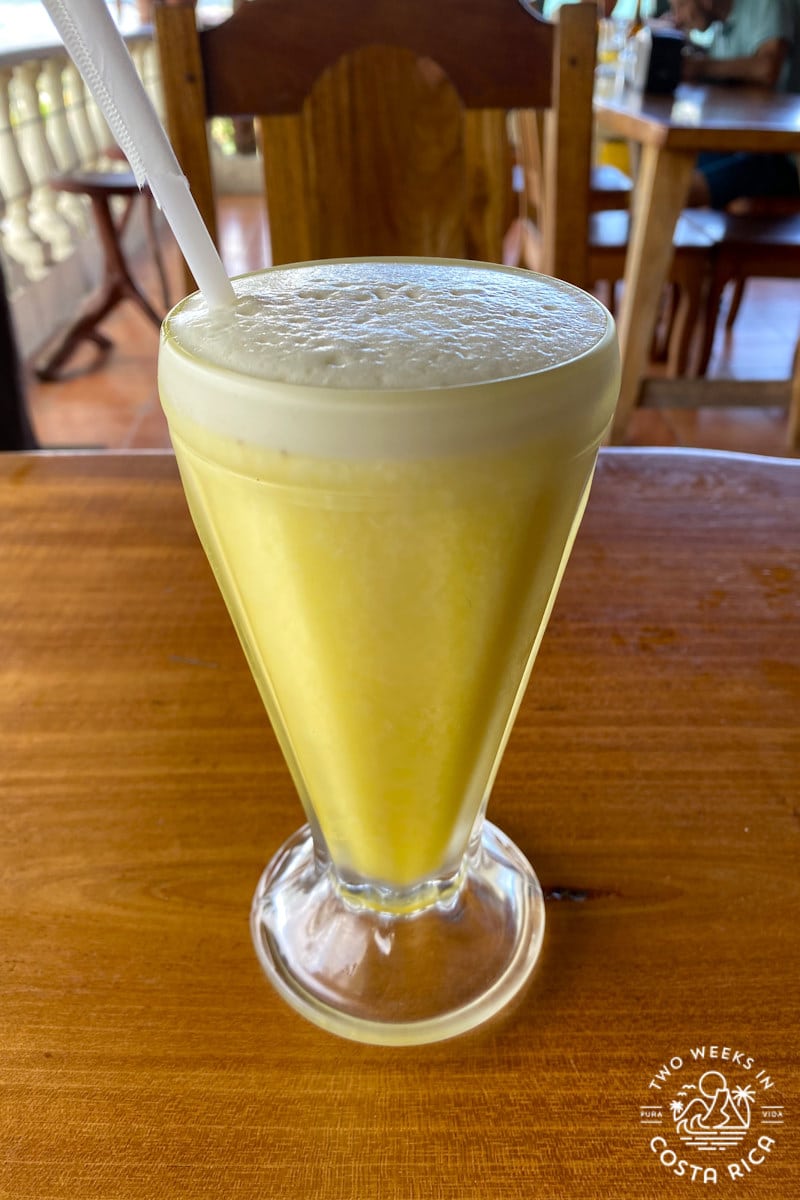 a yellow drink in a tall glass on a wooden table