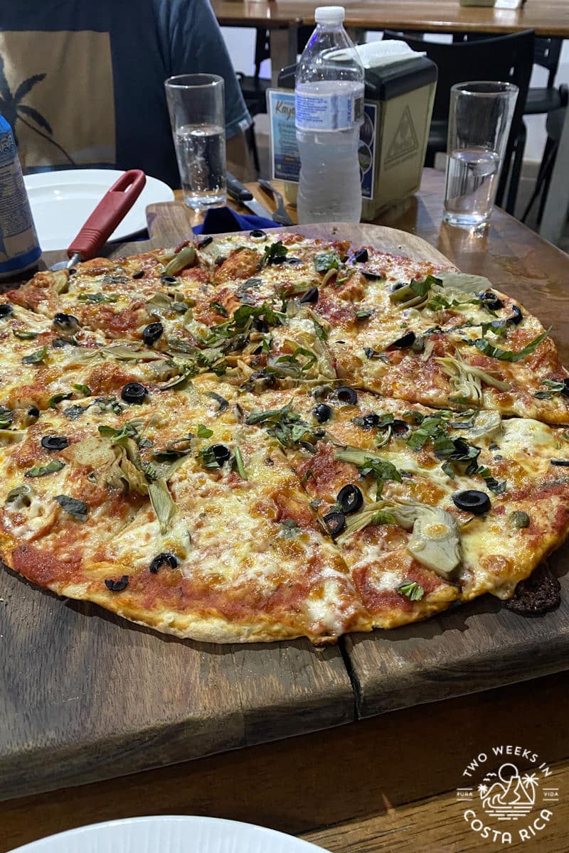a pizza with vegetables on a wooden board