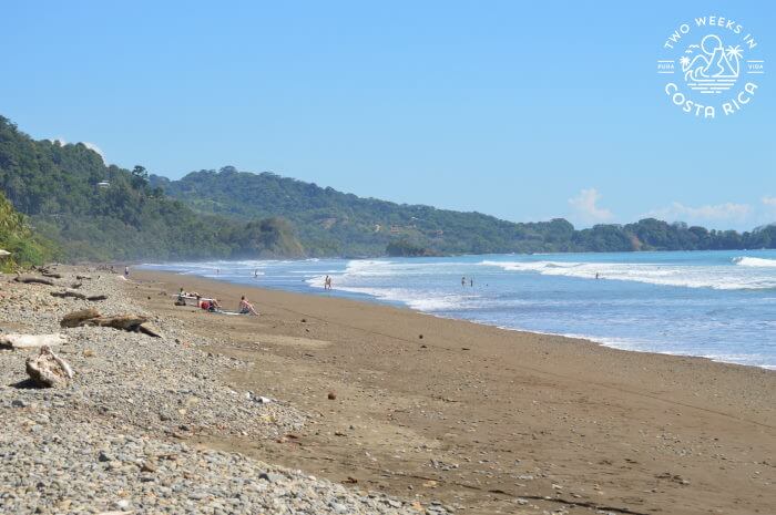 rocky beach blue water and green hills as the backdrop