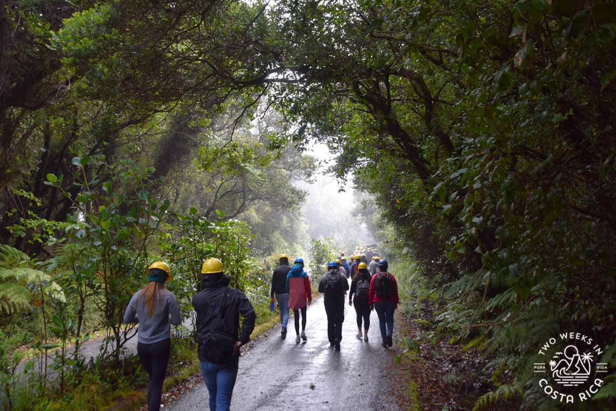 people walking on the trail at poas volcano wearing hard hats