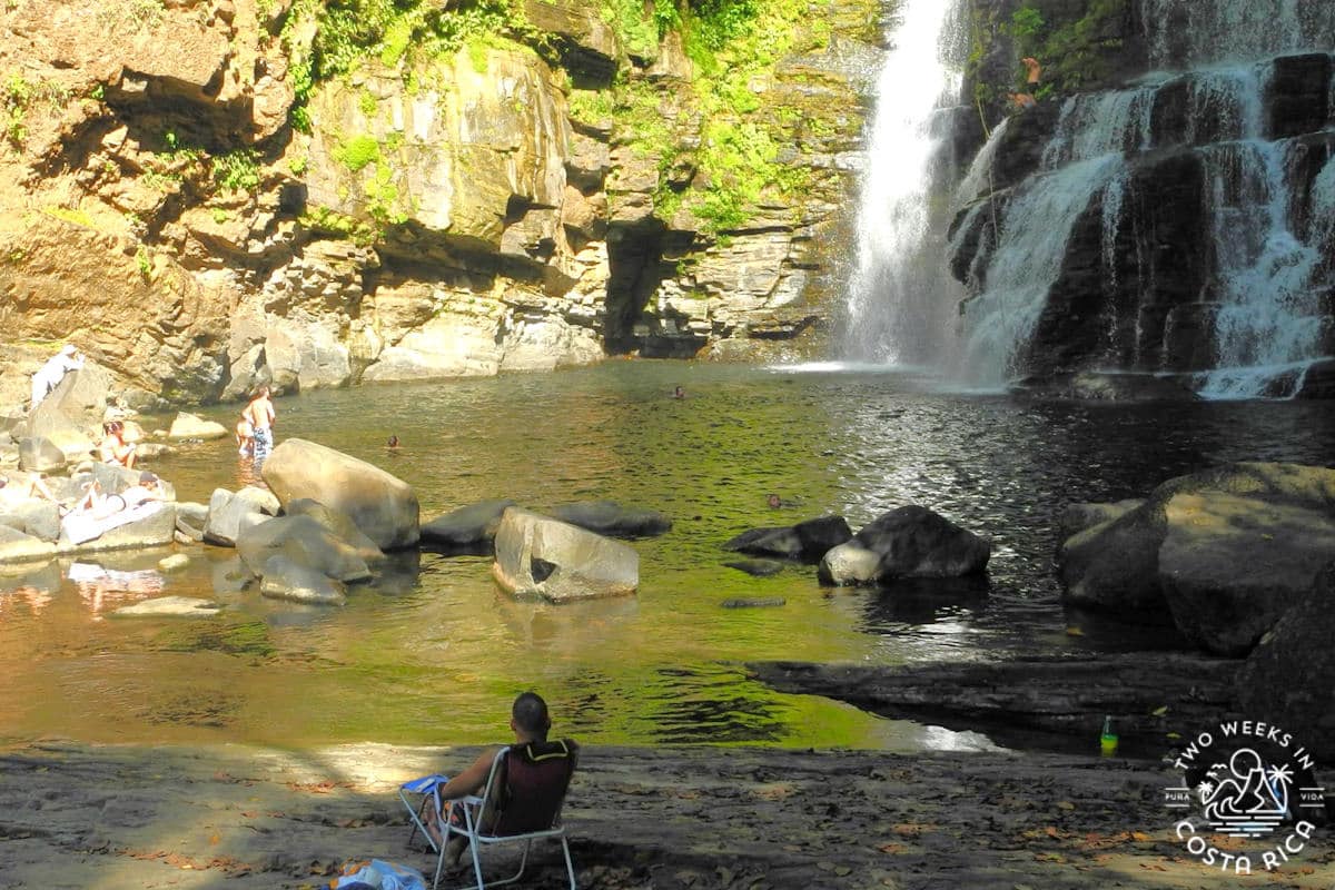 people sitting on the rocks at the nauyaca waterfall on the don lulo side