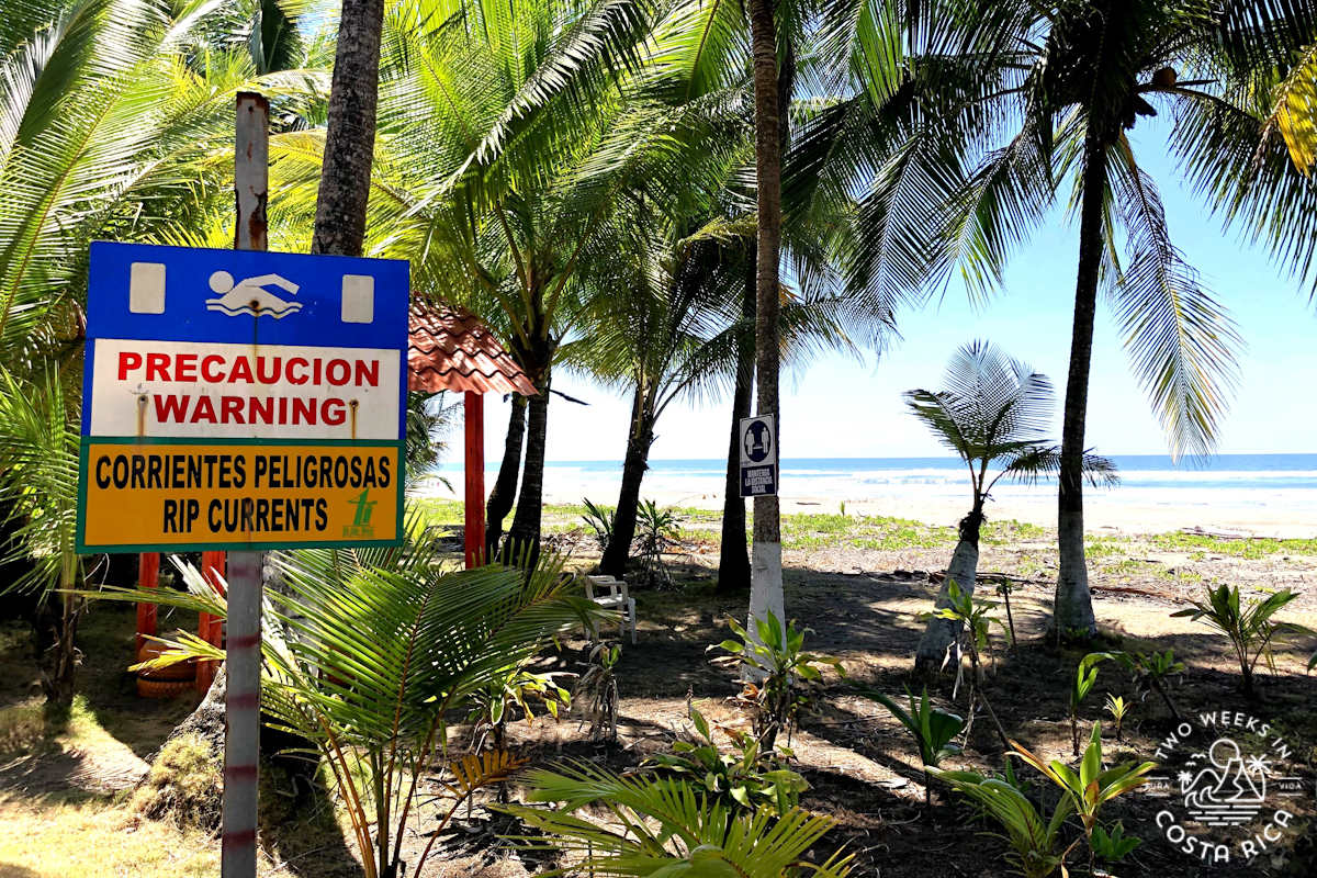a beach with a sign that says caution rip currents