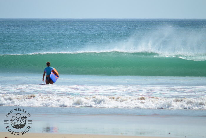 a woman holding a boogie board in the ocean at playa avellanas 