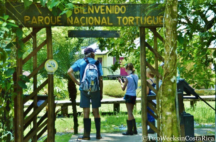 A family standing under the sign for Tortuguero National Park